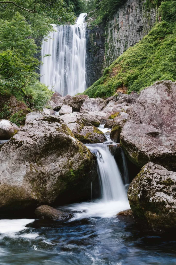 Goto Falls surrounded by lush green moss and forest in Shimamaki, Hokkaido, Japan, during summer.