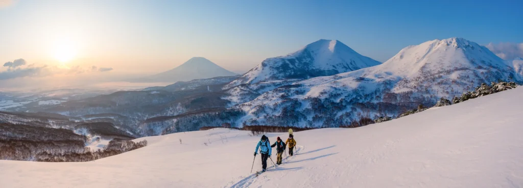 Skiers in the backcountry with mountains in the distance, showing the skill and access needed for ski photography