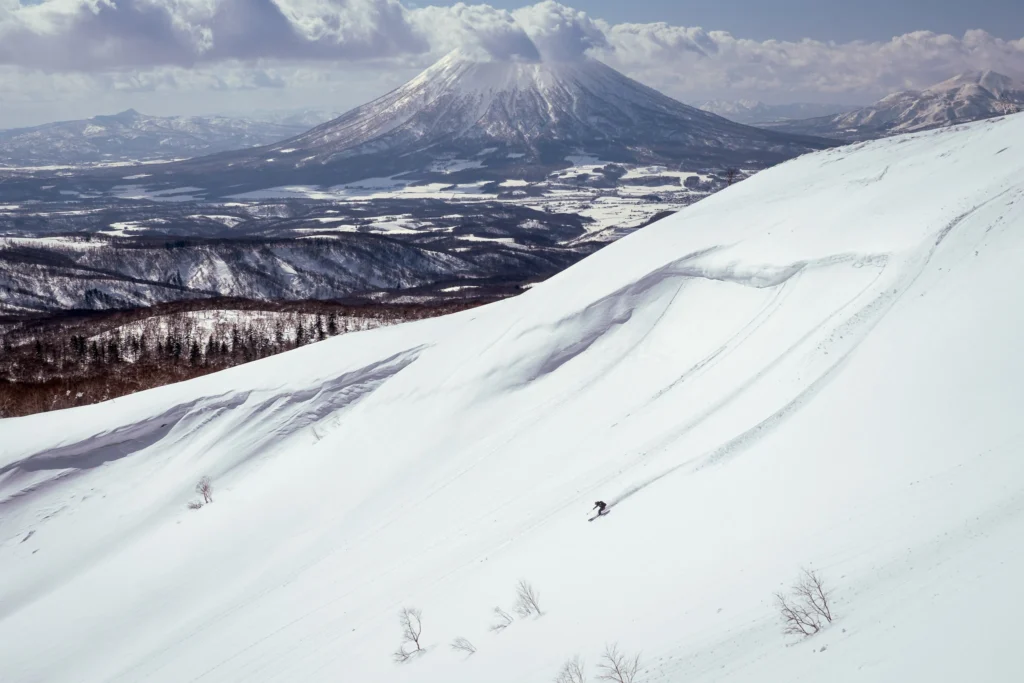 Skier making fresh tracks on a wide slope with Mount Yotei in the background, Japan — example of storytelling in ski photography.