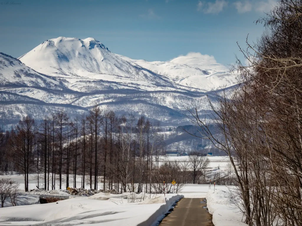 Snow-covered road leading toward the mountains of the Niseko Range in Hokkaido, Japan.