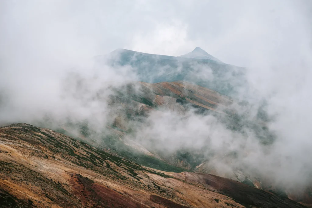 Cloud drifting across the volcanic slopes of Mount Asahidake, revealing layered ridgelines and alpine terrain in Daisetsuzan National Park, Hokkaido.