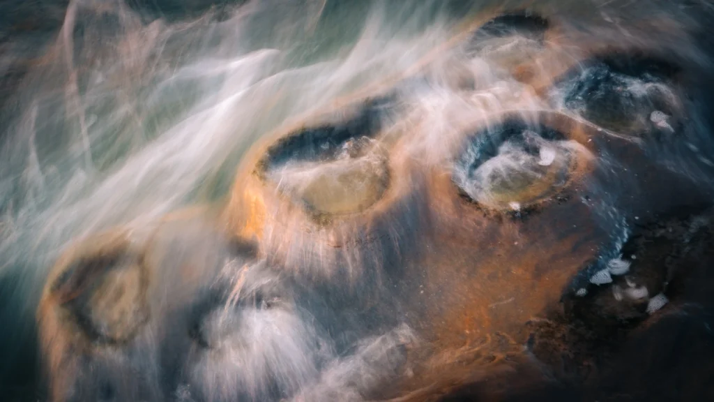 Long-exposure photograph of water flowing around a rock, showing how technical choices create effects beginners don’t yet know to visualise.