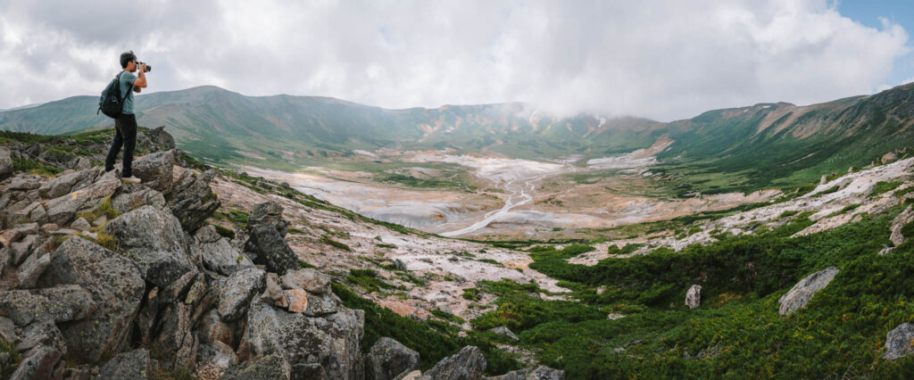 Wide panoramic view into the Ohachidaira caldera, a large volcanic basin in the Daisetsuzan range with braided streams and rugged terrain, Hokkaido, Japan.