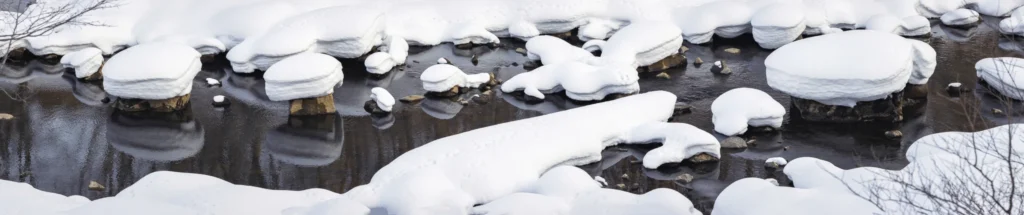 Snow mushrooms forming over rocks in a winter river in Hokkaido